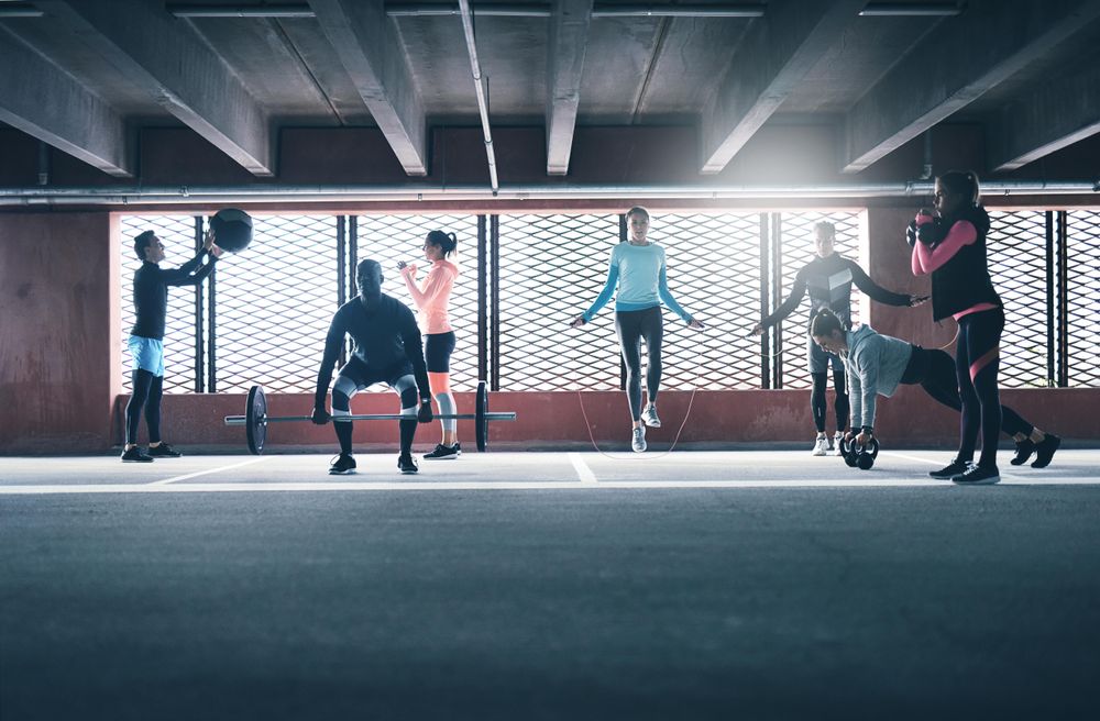 Multi-ethnic group of people doing circuit training in a car park