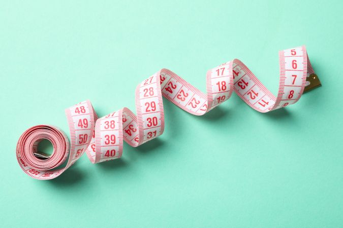 Measuring tape on mint background. Weight loss concept