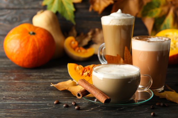 Composition with pumpkin latte, cinnamon and pumpkin on wooden background