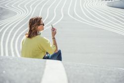 Modern relaxed woman vaping while sitting on marked road