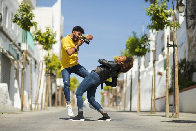 Excited man taking photo of bending girlfriend