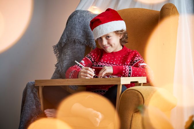 Content kid painting in armchair in Christmas