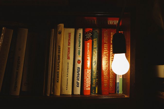 Light bulb beside bookshelf inside dark room