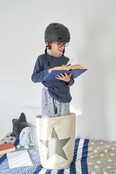 Satisfied boy in helmet reading book in bedroom
