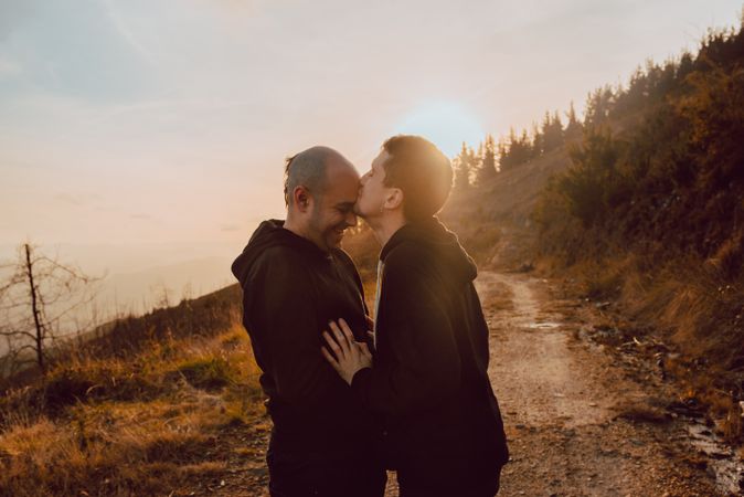 Men hugging and kissing in forest