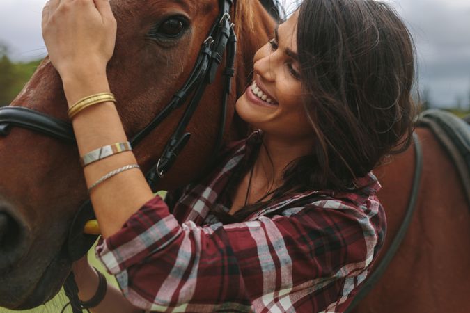 Close up of woman petting the nose of her horse and smiling