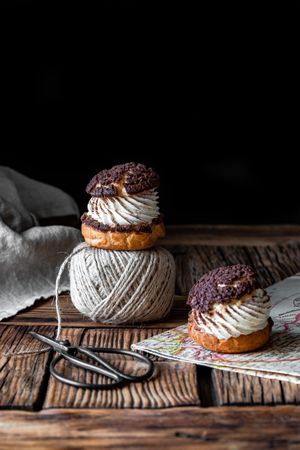 Delicious choux buns and wool threads on wooden table