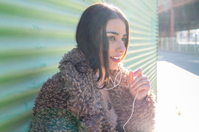 Trendy woman with smartphone near wall