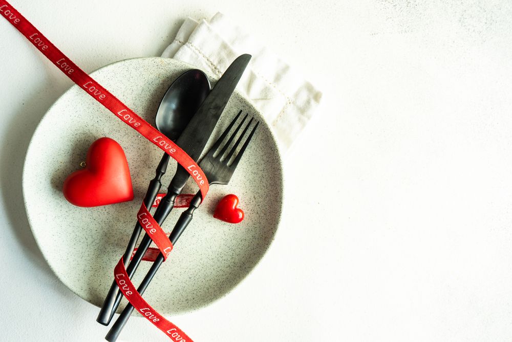 Dark cutlery on ceramic plate with red hearts