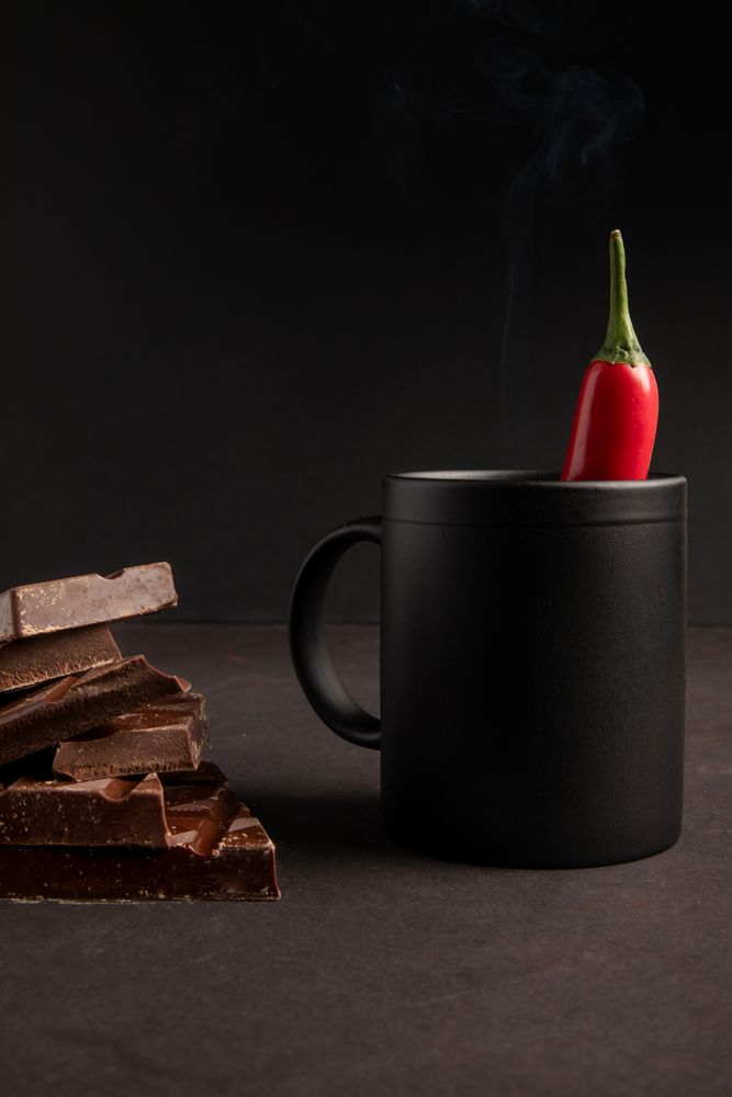 Chocolate near mug with hot drink and pepper