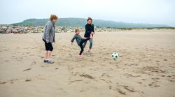 Three generations of women playing soccer on the beach