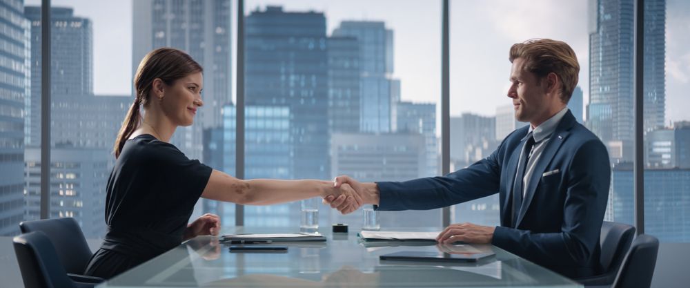 Female and Male Business Partners Sign Successful Deal and Shake Hands in Meeting Room in Skyscraper Office.
