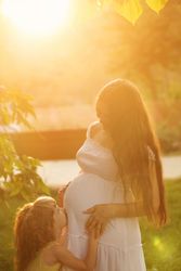 Daughter kissing her pregnant mother’s stomach