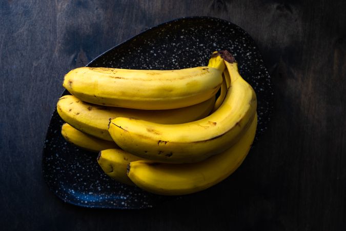 Bunch of bananas on plate on kitchen counter