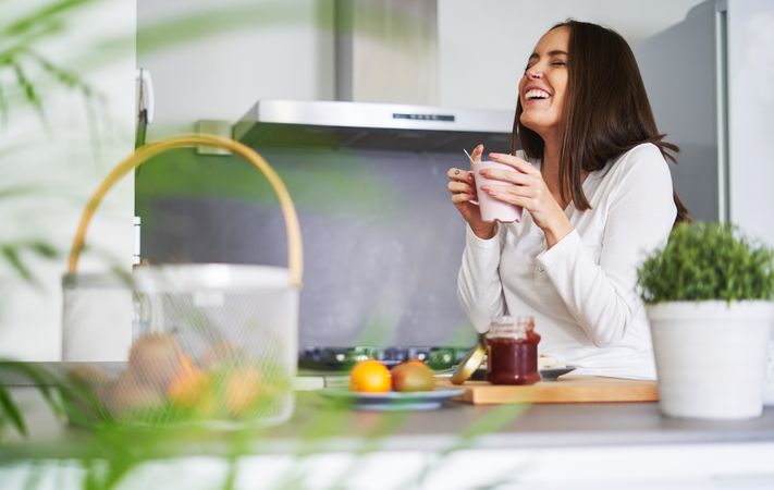 Woman drinking from cup in kitchen