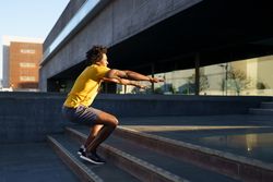 Man doing squats on stairs outside