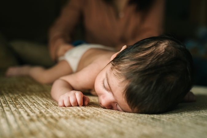 innocent newborn baby in back lying on sofa at home