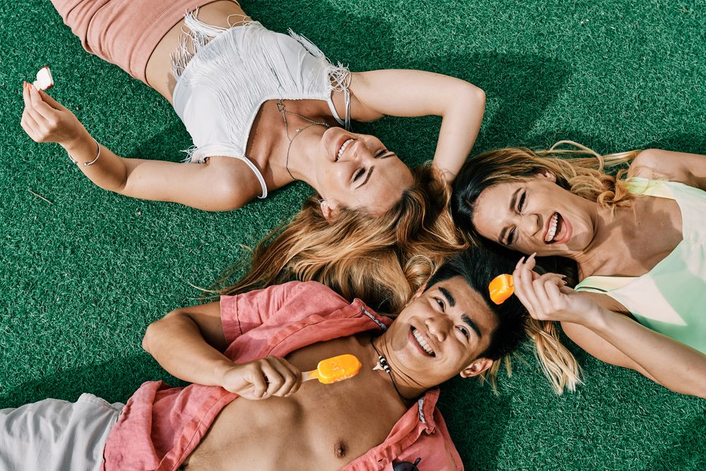 a group of young people having a good time and eating ice-cream lying on grass