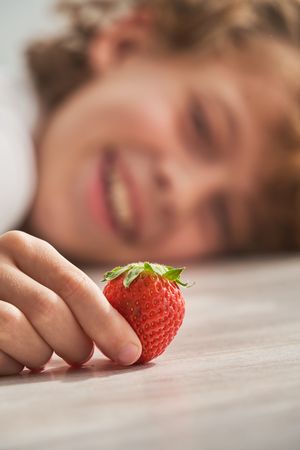 Happy boy with strawberry lying on floor