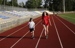 Two siblings walking on running track together