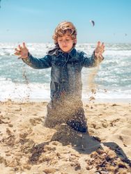 Boy playing with sand on seashore