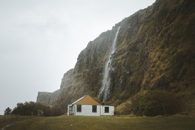 Rural house at foot of huge mossy cliff