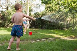 Little kids in swimwear having fun with splashing water