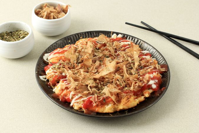 Plate of okonomiyaki served with chilli sauce and mayonnaise