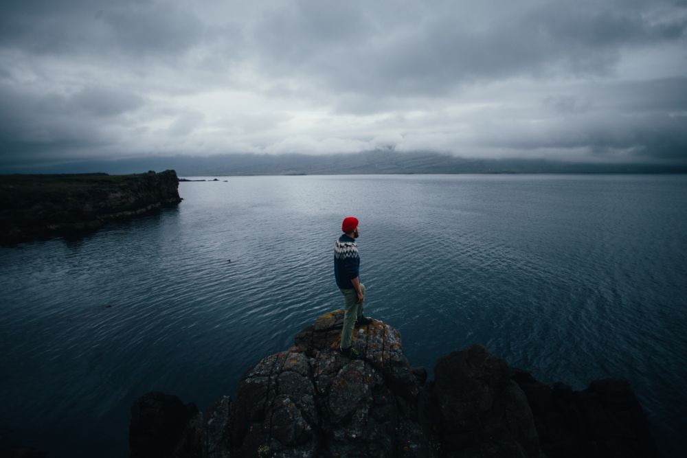 Man standing on edge of cliff on overcast day, landscape