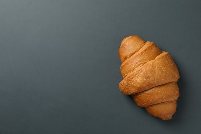 Freshly baked croissant on dark grey background, top view with copy space