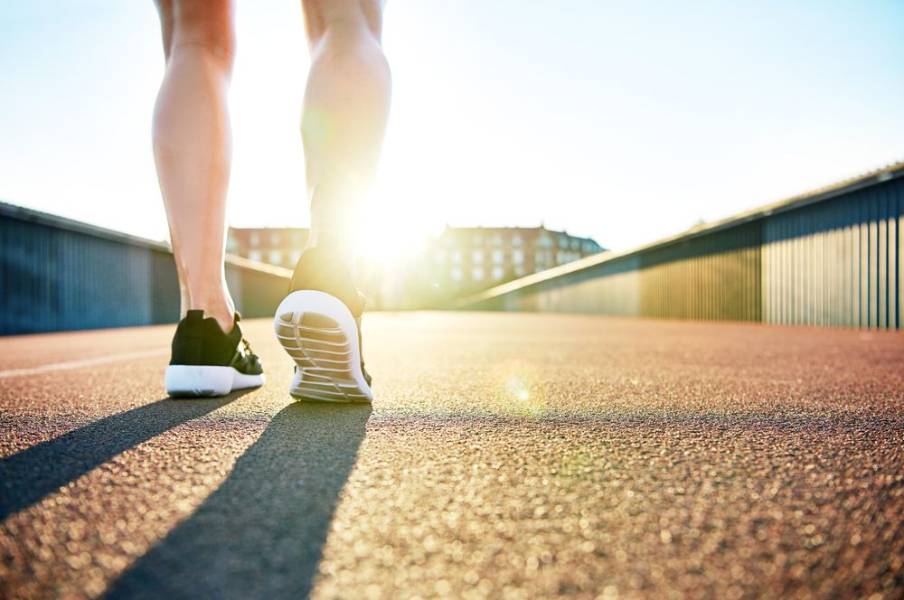 Woman’s calves and running shoes outside in morning sun