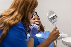 Dental patient checking out teeth in mirror at clinic