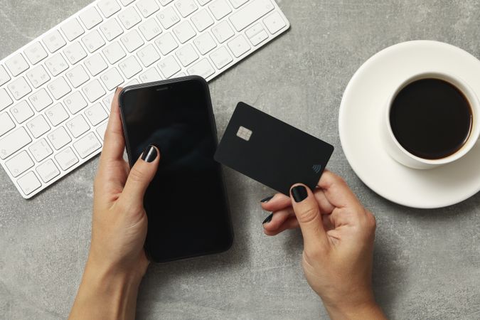 Female hands hold phone and card on gray background