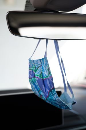 Handmade blue PPE mask hanging on car mirror