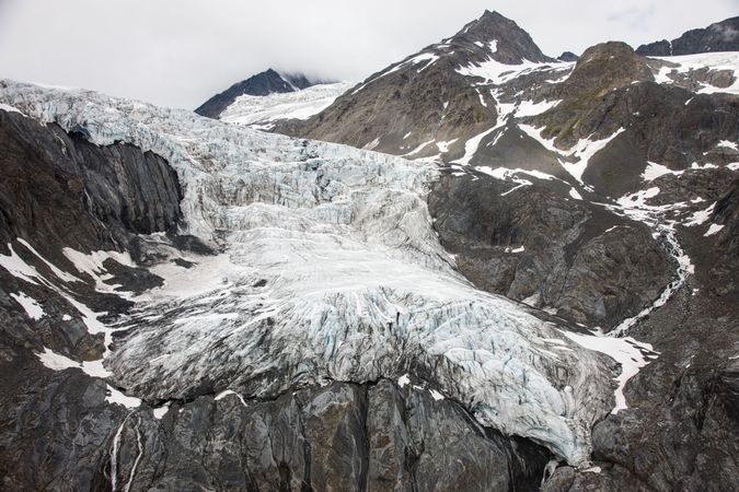 Glacier on rocky brown mountains in Alaska