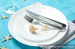 Table setting with seashells and starfishes on turquoise background, close up bYqR9G