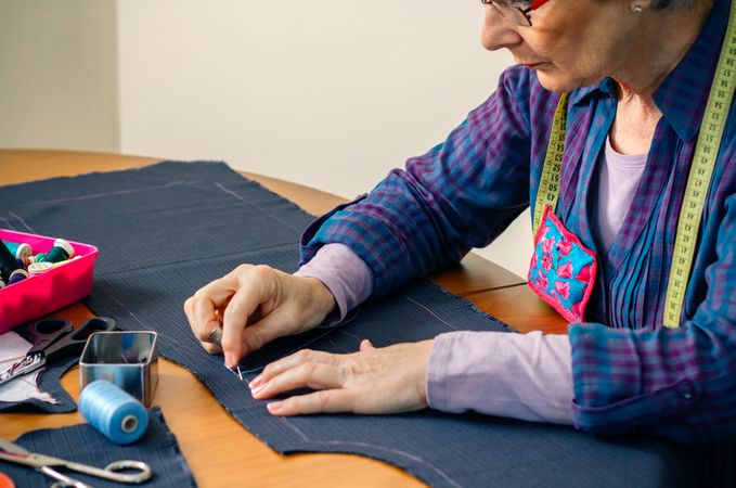 Mature female seamstress sewing cloth