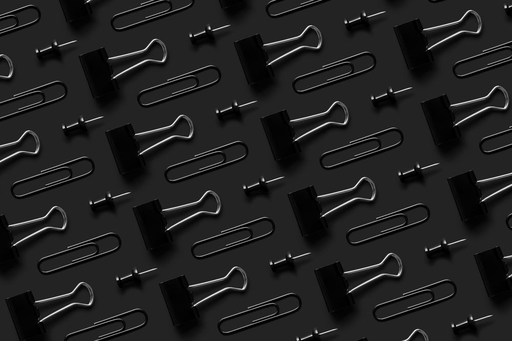 Binder clips and tacks on a dark background