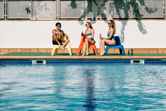 two young women looking at a handsome man by the pool