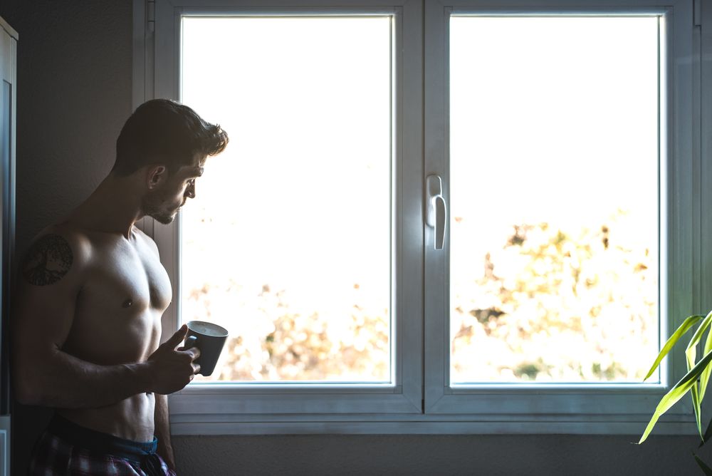 Man standing by a windows with a cup of coffee