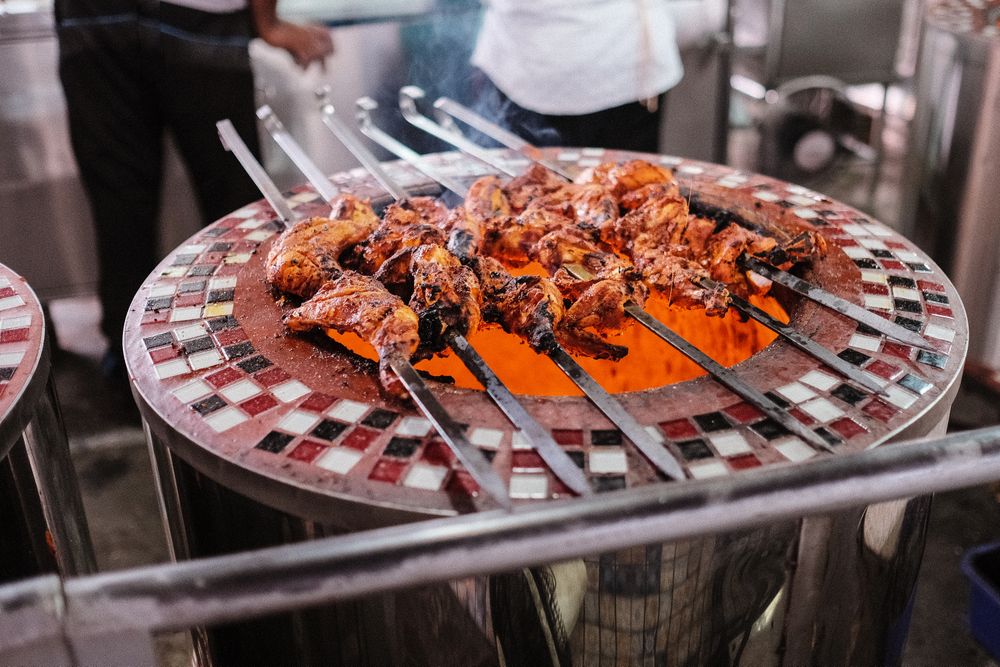 Skewers of meat on a tiled grill