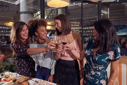 Delighted multiethnic women toasting in restaurant