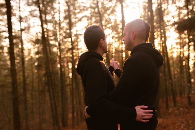 Men hugging in forest at sunset