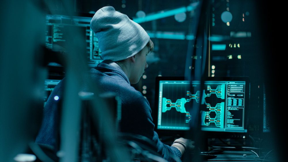 Back View of Teenage Hacker Working in Computer and Infecting with Virus Data Servers of Government Infrastructures.