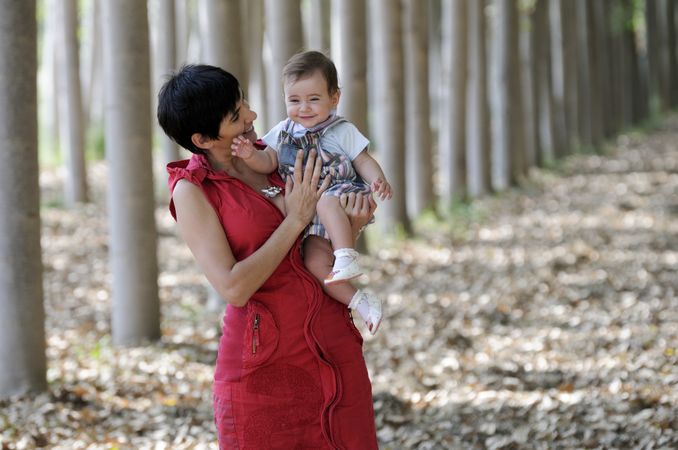 Mother holding cute baby girl in forest