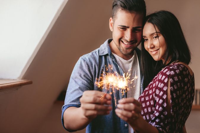 Happy couple celebrating new home purchase with sparklers