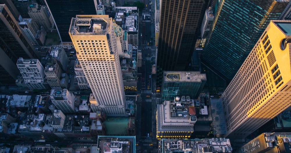 Top Down Aerial View of New York City Streets in Manhattan, Business and Residential Building Roofs. Helicopter Flying Along a Straight Road with Cars, Taxis, Busses and Other Transportation