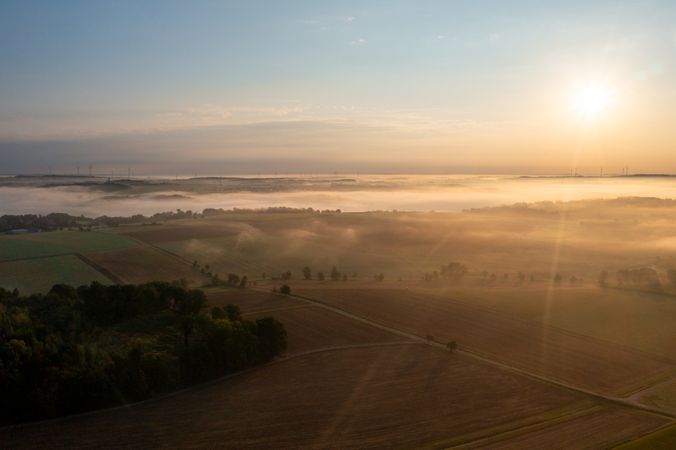 Drone aerial view at sunrise with rolling landscapes covered in fog