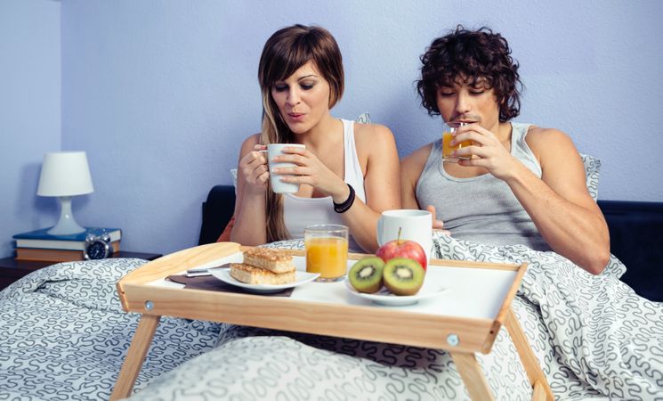Couple having breakfast in bed served on wooden tray