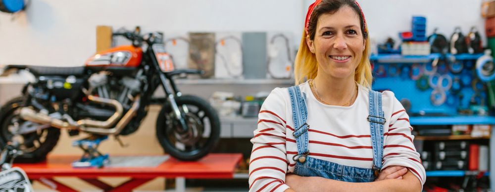 Portrait of mechanic woman standing on motorcycle factory